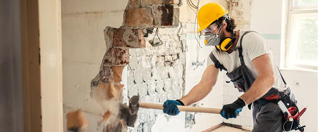 Demolition image of man breaking wall down
