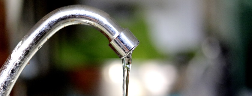 A close up of a sink faucet dripping water.