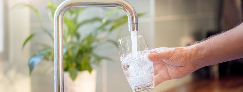 Someone filling a glass of water from the kitchen sink