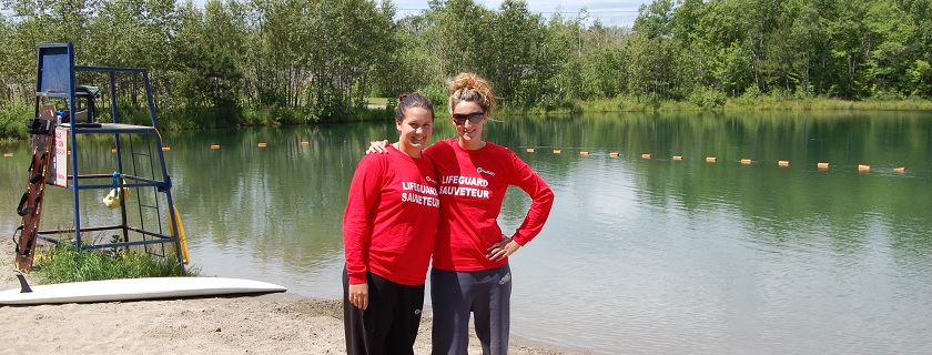 Two female lifeguards standing in front of a lake.