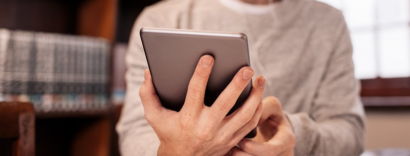 Male hand holding a tablet to vote.