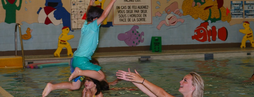 A child jumping into a lifeguard's arms in a pool.