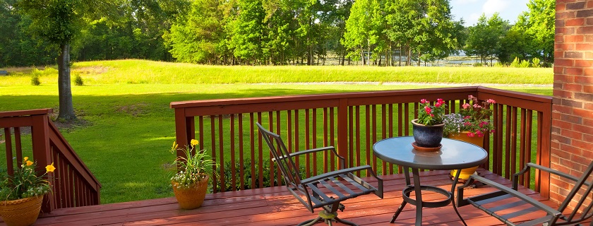A deck with a table and chairs and trees in the background.
